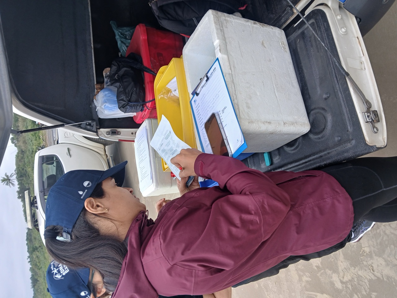 Filling out the sample bag information from the back of a truck at the beach in Cananéia–Iguape–Peruíbe, Brazil, August 2026.
