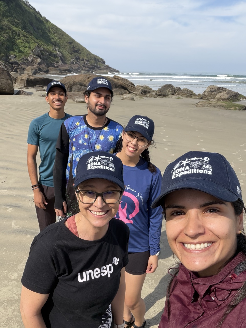 The Cananéia–Iguape–Peruíbe sampling team, Brazil, on the beach after their first sampling event, August 2026. From foreground to background: Jeniffer Teles, Prof. Giovana Bertini, and three volunteer PhD students from the São Paulo State University (UNESP), Campus of Registro: Esthephany Miranda, Lucas Santana and Johnatas Carvalho
