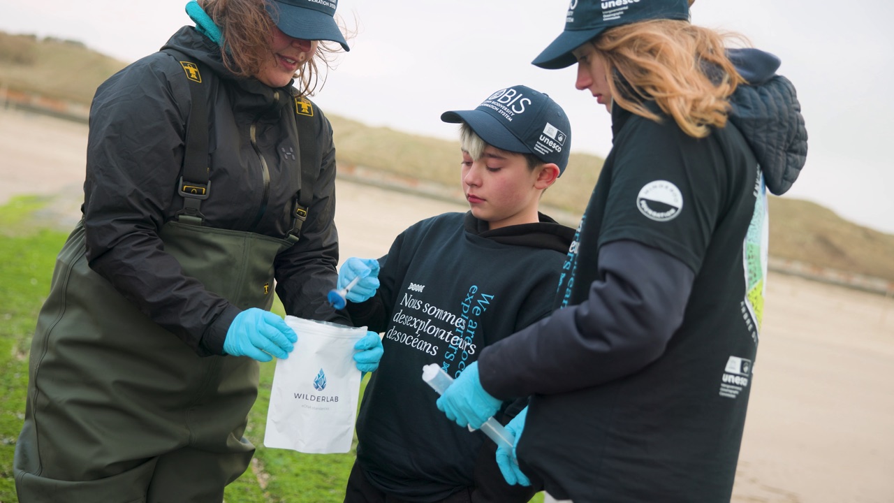 Team members examining a Wilderlab sampling pouch and preservation syringes together on site